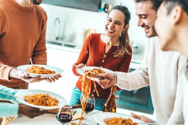 Happy group of friends eating pasta dinner