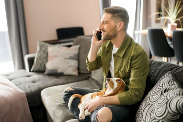 man on couch with dog talking on the phone