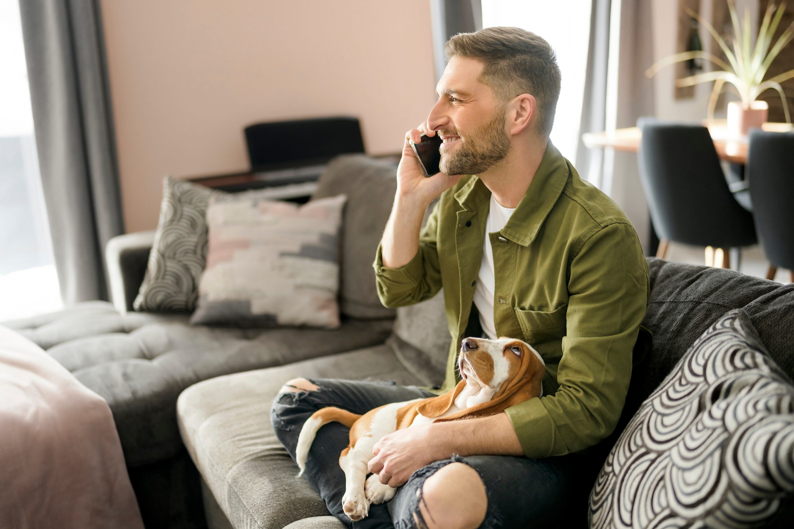 man on couch with dog talking on the phone